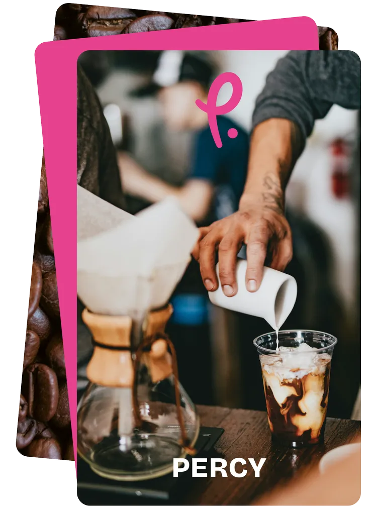 Barista pouring milk into an iced coffee behind the counter of a coffee shop